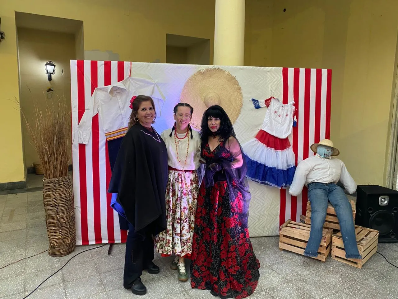 Tres asistentes posando frente al rincón fotográfico con vestimenta típica y de disfraz
